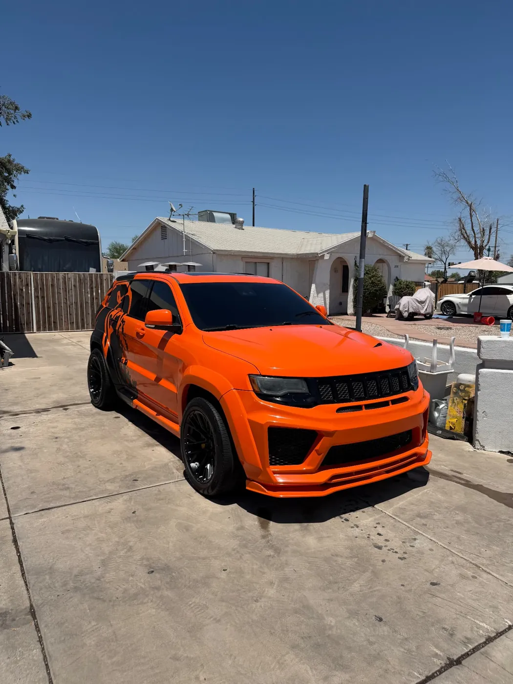 Orange Jeep Grand Cherokee Trackhawk with a widebody kit detailed in a Phoenix, Arizona driveway