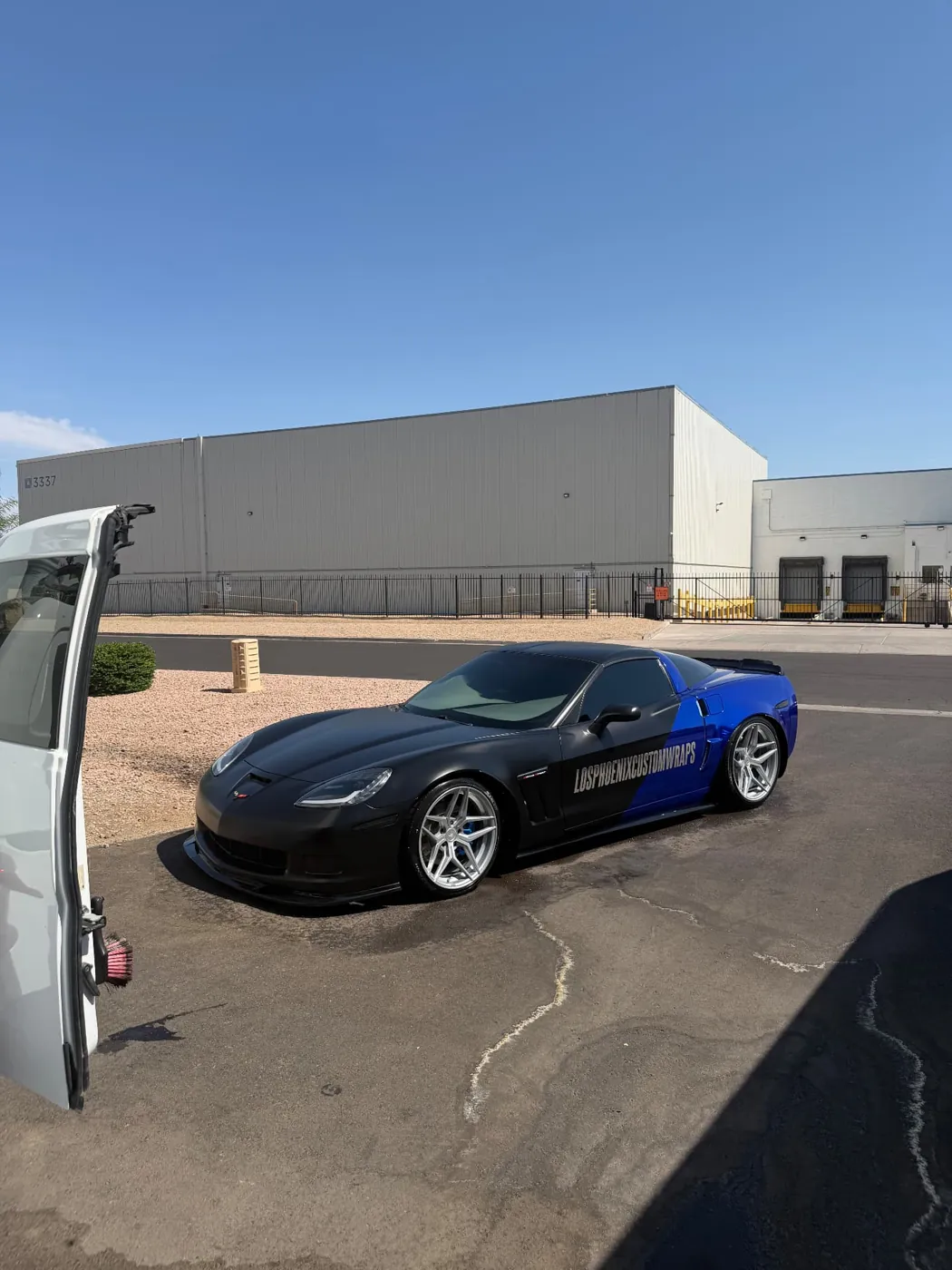 Matte black and blue wrapped Chevrolet Corvette detailed on-site next to the Carson's mobile detailing van in Phoenix