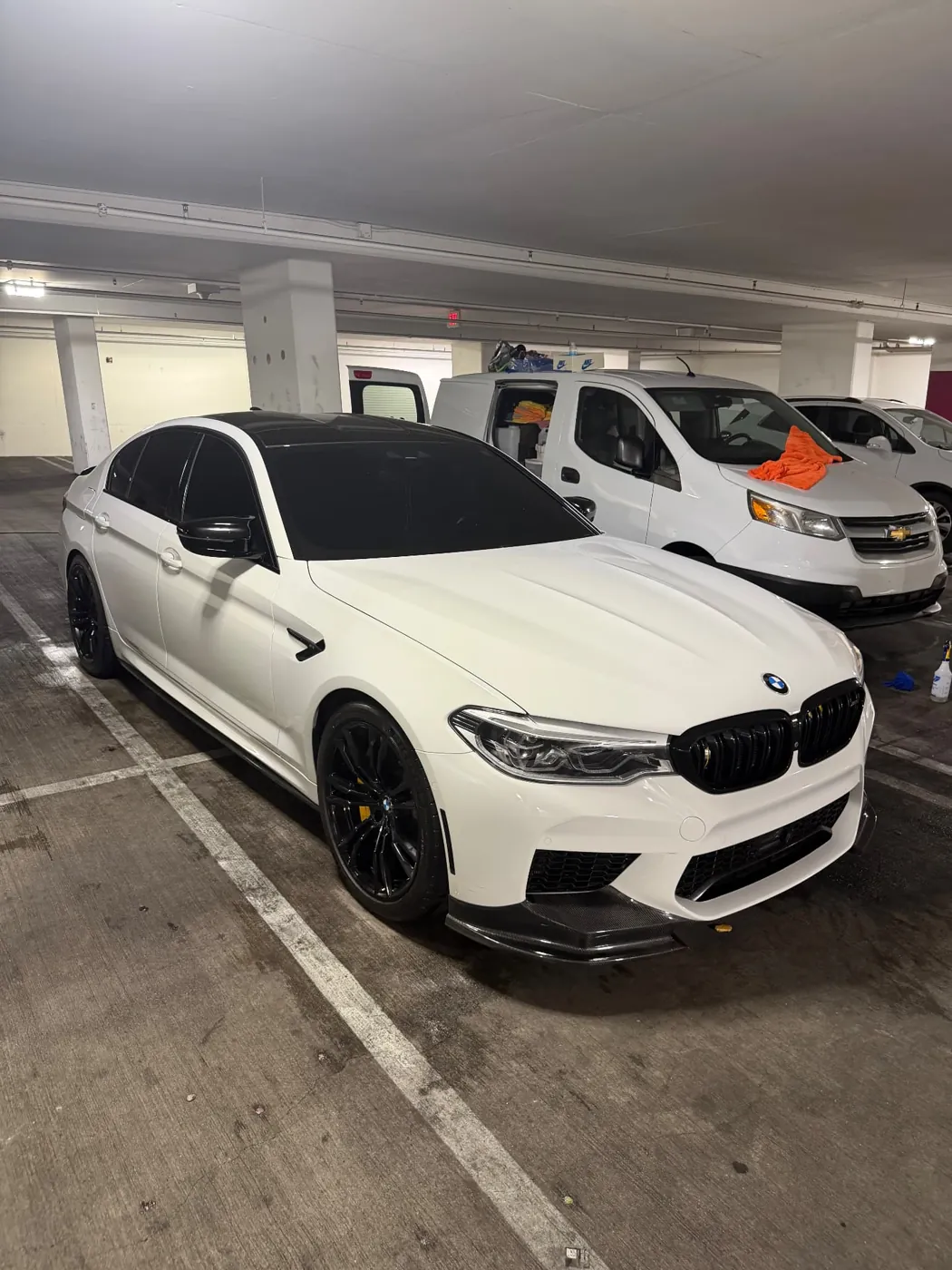 White BMW M5 Competition freshly detailed with gloss black trim in a Scottsdale parking garage