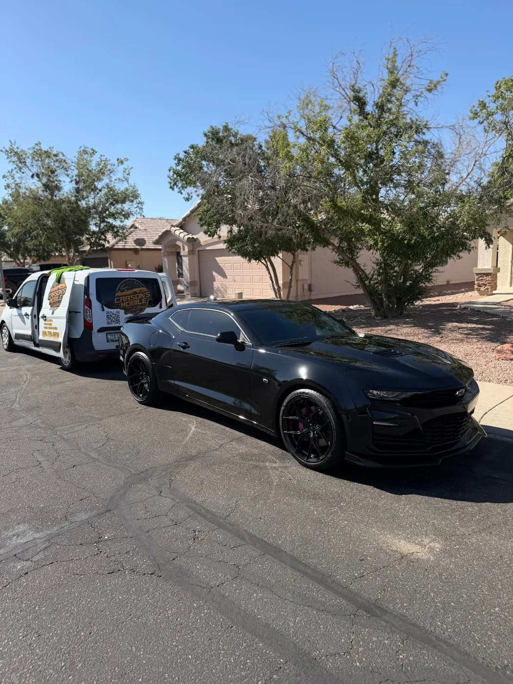 Black Chevrolet Camaro SS with mirror reflections after a mobile detail beside the Carson's van in Surprise, AZ